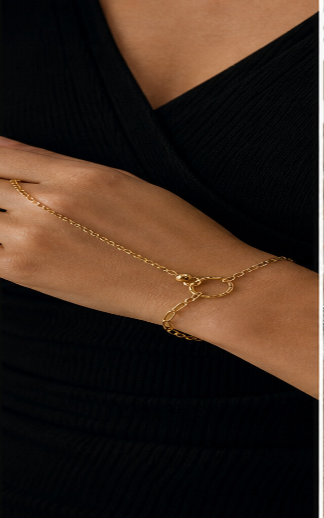 Goudkleurige handketting en donkere outfit als voorbeeld van niet verkleurende sieraden
